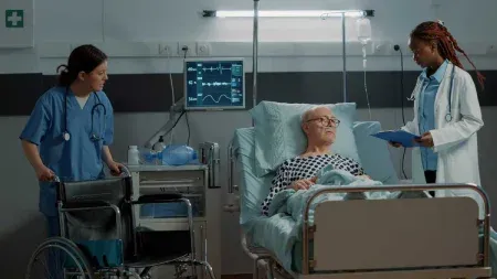 Medical-workers-standing-next-to-man-in-hospital-bed-Medical-Healthcare-Ergonomics-Safety-Training.webp